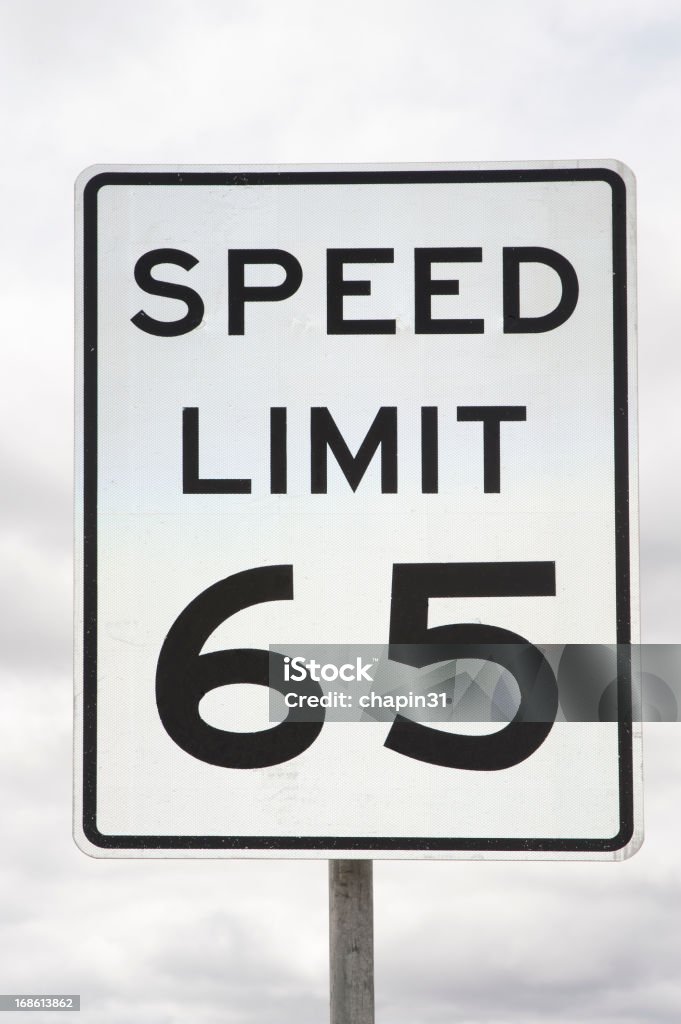 Speed Limit Sign 65 Miles Per Hour A street sign that says "Speed Limit 65" is posted on a yellow metal post and shot against a cloudy sky.  There is plenty of copy space available. Number 65 Stock Photo