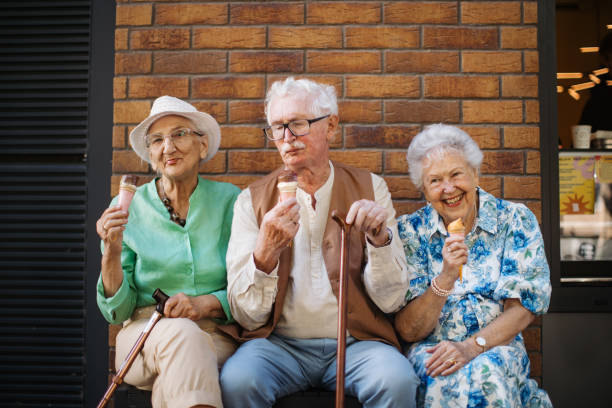 Portrait of three senior friends in the city, eating ice cream on a hot summer day. stock photo