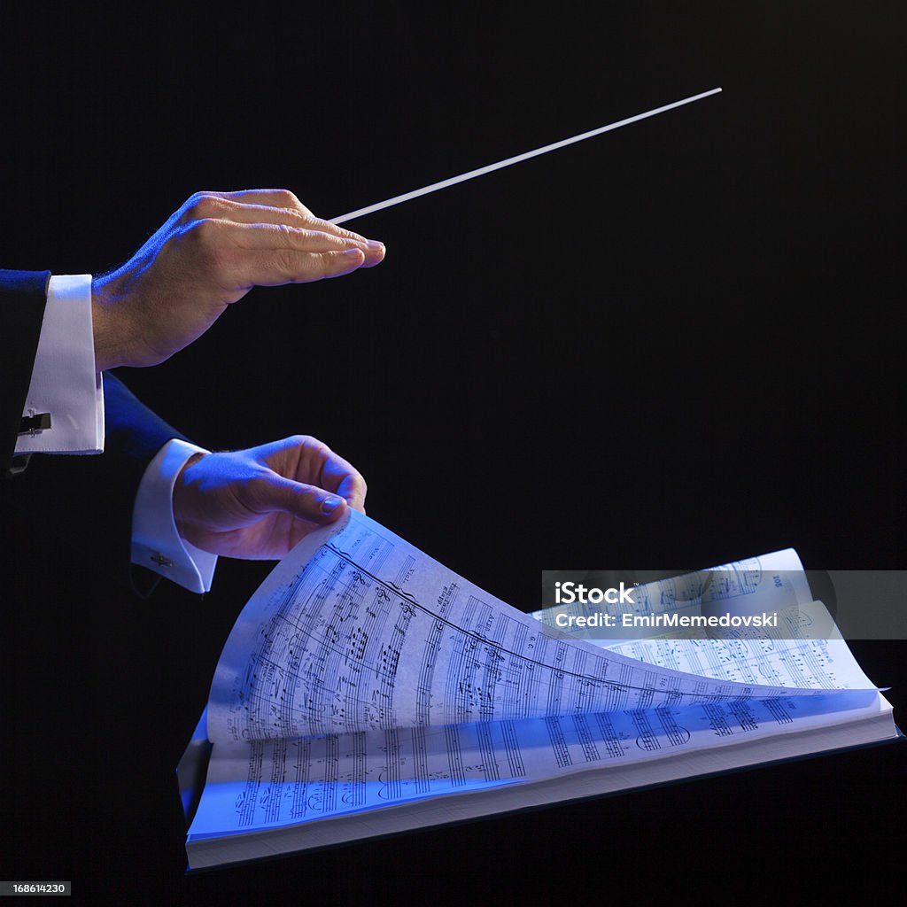 Hands of a conductor with a baton and musical book Conductor's hands with a baton Musical Conductor Stock Photo