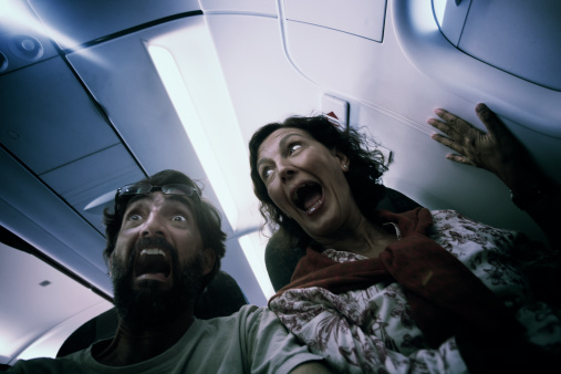 Two passengers scream in fear in what could be a plane accident, or them just being over conscious. Motion blur and shallow depth of field with focus on man's eyes.