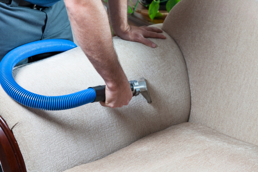 Man cleaning sofa  with steam cleaning in home