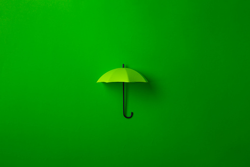 Green umbrella isolated on purple background. Invesment, business, summer concept