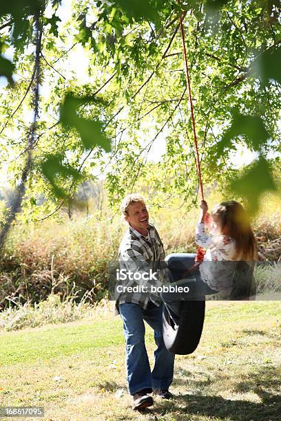 Photo libre de droit de Père Tenue Fille Sur Balançoire Pneu banque d'images et plus d'images libres de droit de Adulte - Adulte, Balançoire, Balançoire pneu