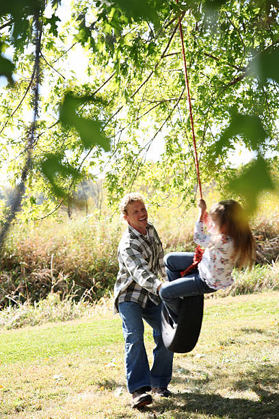 istock father pushing daughter on tire swing 168617095