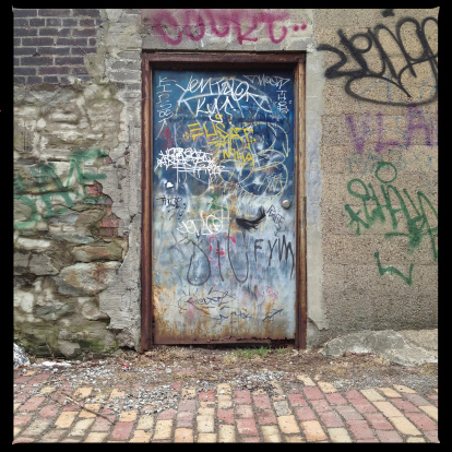 Graffiti Covered door in back alley.    Photographed with an iPhone and processed in Instagram.