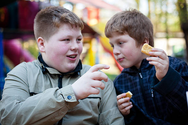 istock Unhealthy Eating: two overweight boys eating chicken nuggets 168619555