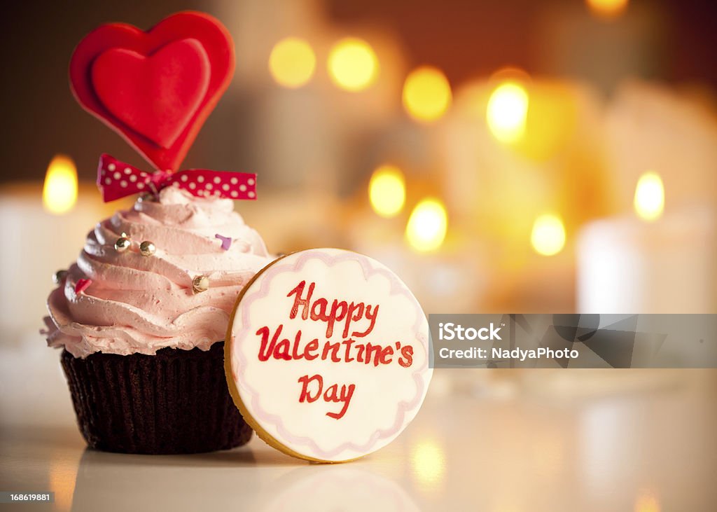 Sweet Valentine Cute Valentine's cookie with Happy valentine's day written on it next to Valentine's cupcake. Valentine's Day - Holiday Stock Photo