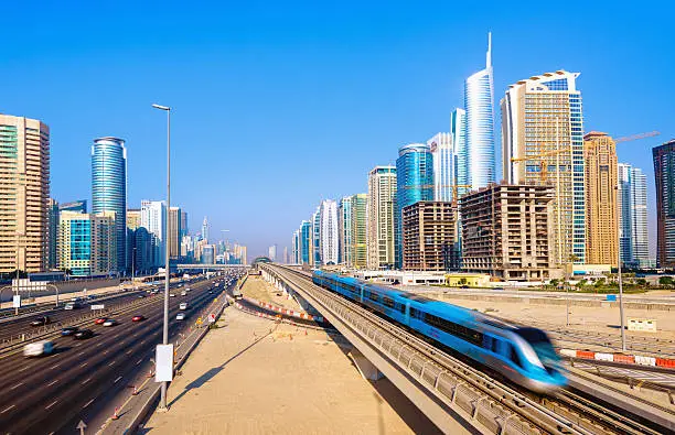 Elevated view on the speeding Metro and traffic on the 14-lane Sheikh Zayed Road (E11)  into Megacity Dubai, UAE. Long exposure, motion blur.