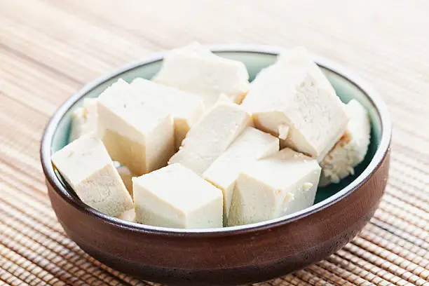 cubes of Tofu, marinating  in a small  bowl, asian style