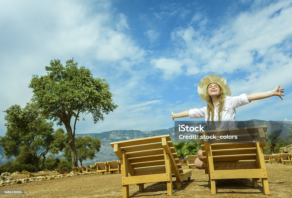 getting away from it all happy free woman with arms raised sitting on sunbed. 20-29 Years Stock Photo