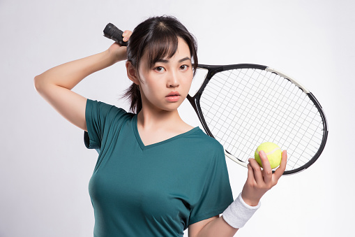 Woman in Tennis Attire Engaging in Tennis Training against Gray Background