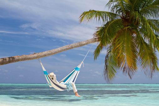 A young man is relaxing in a hammock by the beach.