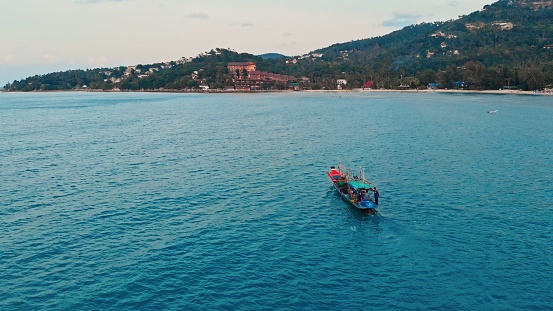 Aerial tracking small fishing boat motoring in Costa Rica bay at speed with tropical mountains background. Wide top view of beautiful ocean in Costa Rica and fishing Fishing and relaxing in Costa Rica