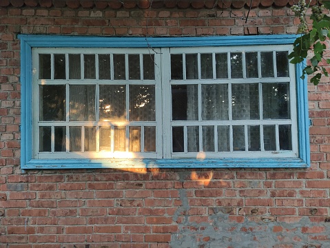 Old wooden window on the brick wall background in evening