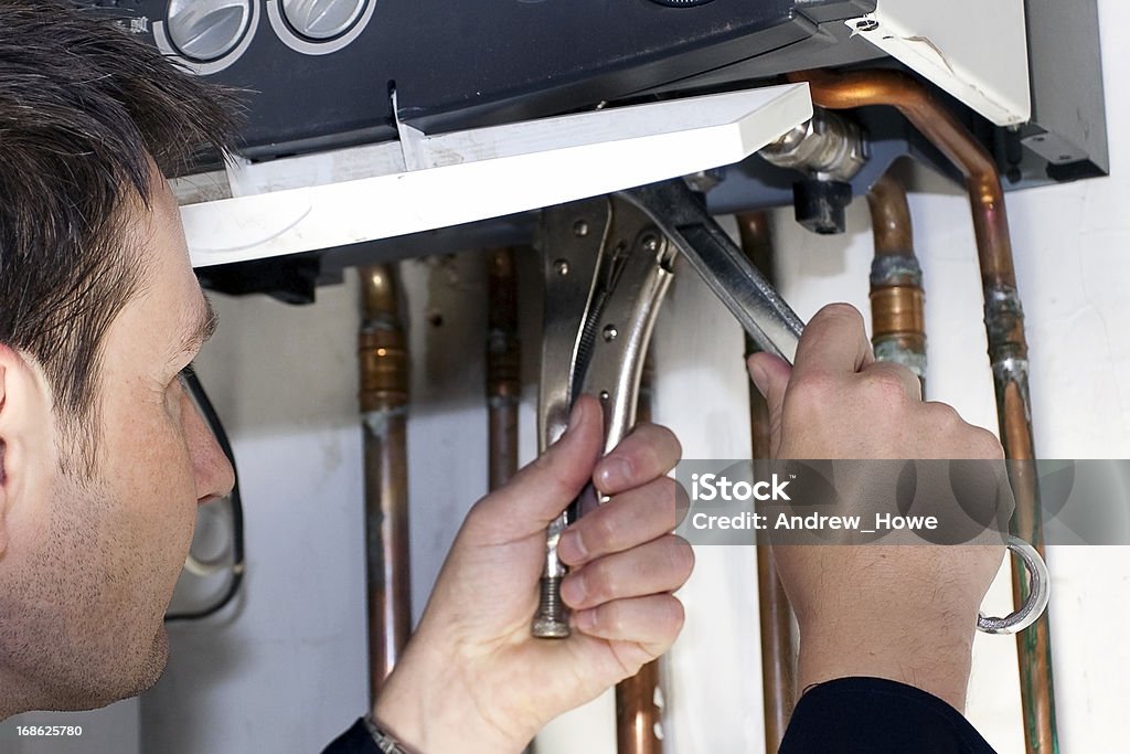 Plumber at Work Plumber working on a water boiler Repairing Stock Photo