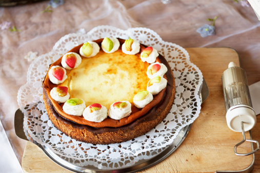 homemade cheesecake, decorated with whipped cream and little fruits made of marzipan