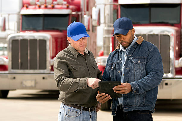 Tablet Computer Review A royalty free image from the trucking industry of two truck drivers having a meeting using a tablet computer. trucking stock pictures, royalty-free photos & images