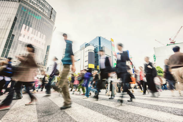 Commuters Shibuya Crossing,Tokyo Japan People walking over famous zebra crossing at Shibuya Crossing in Downtown Tokyo. Long exposure. Motion Blurred. Tokyo, Japan. tokyo crowds on the famous shibuya crossing japan stock pictures, royalty-free photos & images
