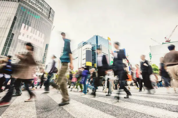 People walking over famous zebra crossing at Shibuya Crossing in Downtown Tokyo. Long exposure. Motion Blurred. Tokyo, Japan.