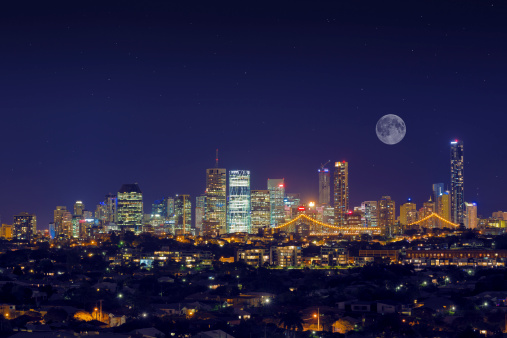 Image of Brisbane skyline looking from the East with full moon and stars just after sunset. 