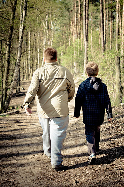 rear view of two overweight boys march through the forest