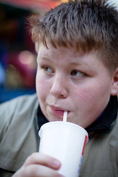 istock Unhealthy Eating: redhead overweight teenage boy with soft drink 168629214
