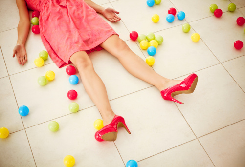 Unconscious woman lying down on the floor with many colored balls.