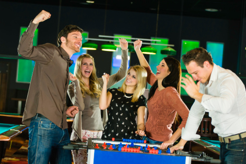 Group of young adults  playing foosball.
