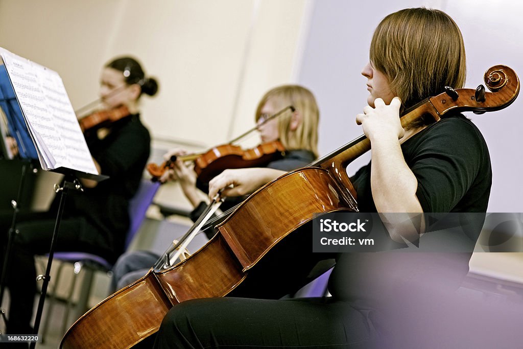 Teenagers Playing on Classical School Concert Teenager playing cello in orchestra. Orchestra Stock Photo