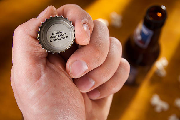 Beer Bottle Cap Message Fun image of a bottle cap with a great message. The setting is a bar seen with some interesting light on the the bar's counter top that has a bottle and some popcorn laying about it. Useful for any beer theme. bottle cap stock pictures, royalty-free photos & images