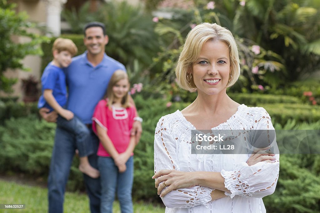 Fiducioso donna con famiglia In Background - Foto stock royalty-free di Braccia incrociate