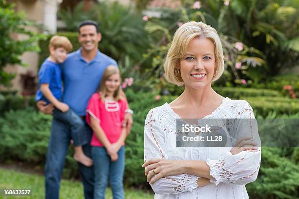 Fiducioso Donna Con Famiglia In Background - Fotografie stock e altre immagini di Braccia incrociate - Braccia incrociate, Famiglia, Rivolto verso l'obiettivo