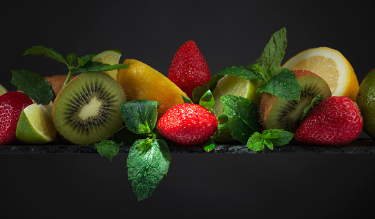Fresh fruits and berries on a black background. Copy space.