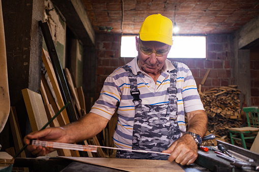 Senior carpenter measuring the furniture he making at his workshop