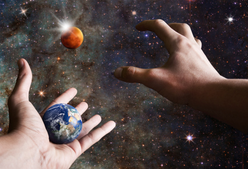 male hand is reaching out to grab planet Mars while other holding earth ,colonization concept