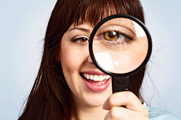 istock Laughing woman looks through magnifying glass 168635483