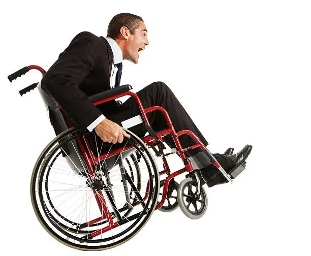 Disability isn't getting this excited businessman down! He "wheelies" in his wheelchair. Isolated on white.