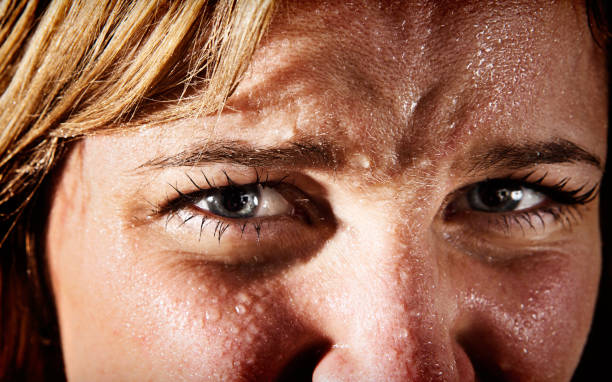 Close-up of perspiring, tense, frowning young blonde woman Close up of  a young blonde woman, covered in perspiration, frowning, tense and nervous.  sweat stock pictures, royalty-free photos & images