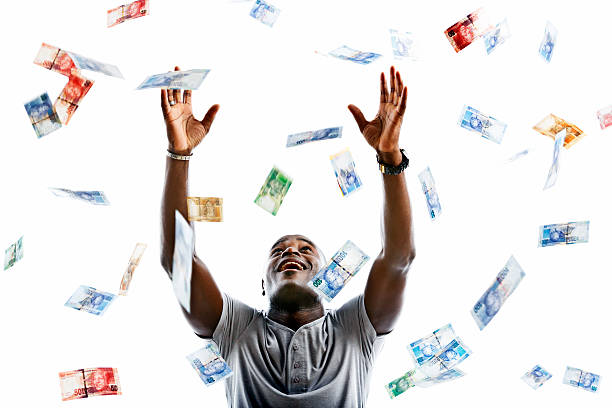 Ecstatic man catching raining banknotes A happy man looks up smiling as he tries to catch hundreds of falling banknotes. The banknotes are varied denominations of the new South African currency featuring South African statesman, Nelson Mandela. Isolated on white.  african currency stock pictures, royalty-free photos & images