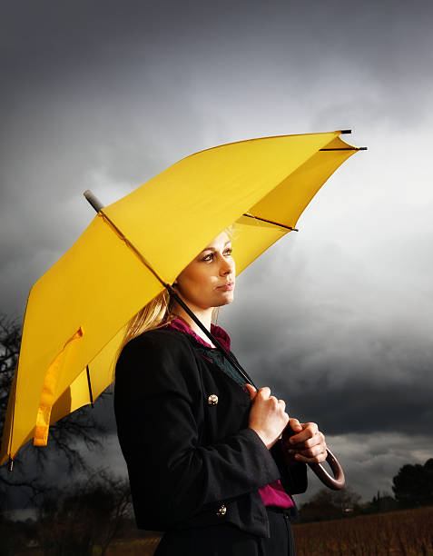 istock beautiful blonde with sunny yellow umbrella against dark thunderclouds 168639615