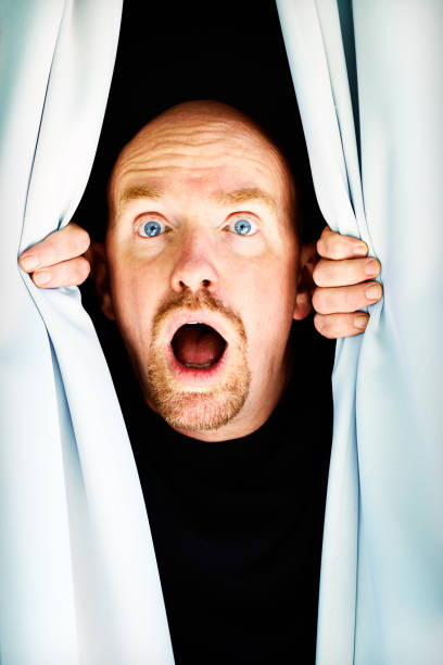 istock Mature man looking through curtains gasps in horror 168639639