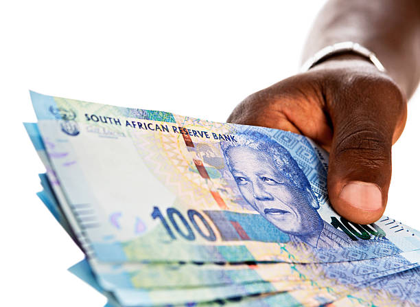 istock Masculine hand holds out bundle of Hundred Rand banknotes 168640008