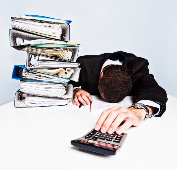 istock Exhausted businessman collapses over desk, reaching for his calculator 168640085