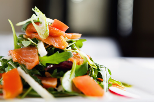 A salad made up of smoked salmon, salad leaves and radishes, appetizingly plated and ready to eat in a modern restaurant. 