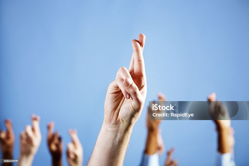 Man's hand with superstitiously Скрестив пальцы, более в синем фоне - Стоковые фото Удача роялти-фри