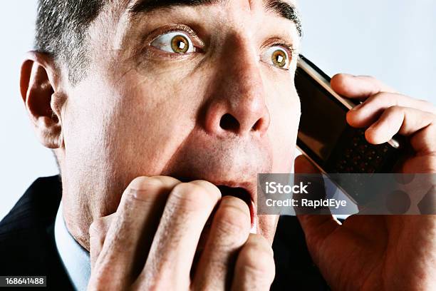 Shocked Businessman Biting Nails In Panic At Phone Call Stock Photo - Download Image Now