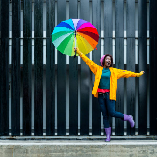 cantare sotto la pioggia - candid women african descent umbrella foto e immagini stock