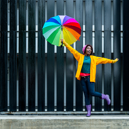 Playful young girl with a colorful umbrella in the city.