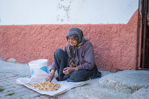 Seydişehir-Konya: Turkey September 1 ,2023  Senior Anatolian woman cleaning white kidney beans on the street front of door in a village in Konya.Şeydişehir.