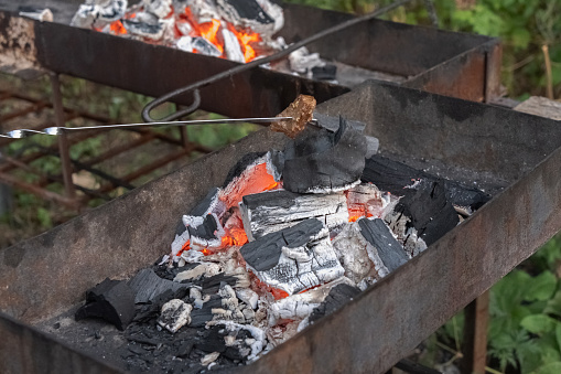 Metal grill with smoldering coals for frying meat or vegetables in the open air. Preparing for a picnic